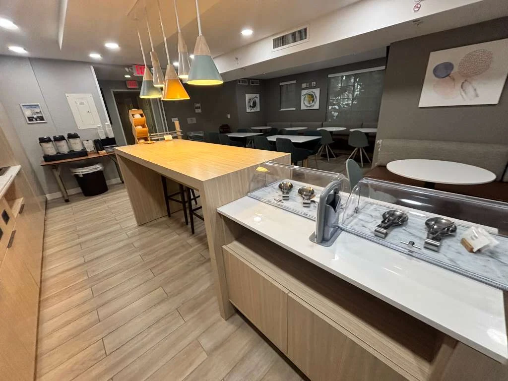 Breakfast servery and seating at a Weston area hotel, with new tile flooring, buffet millwork and pendant lighting