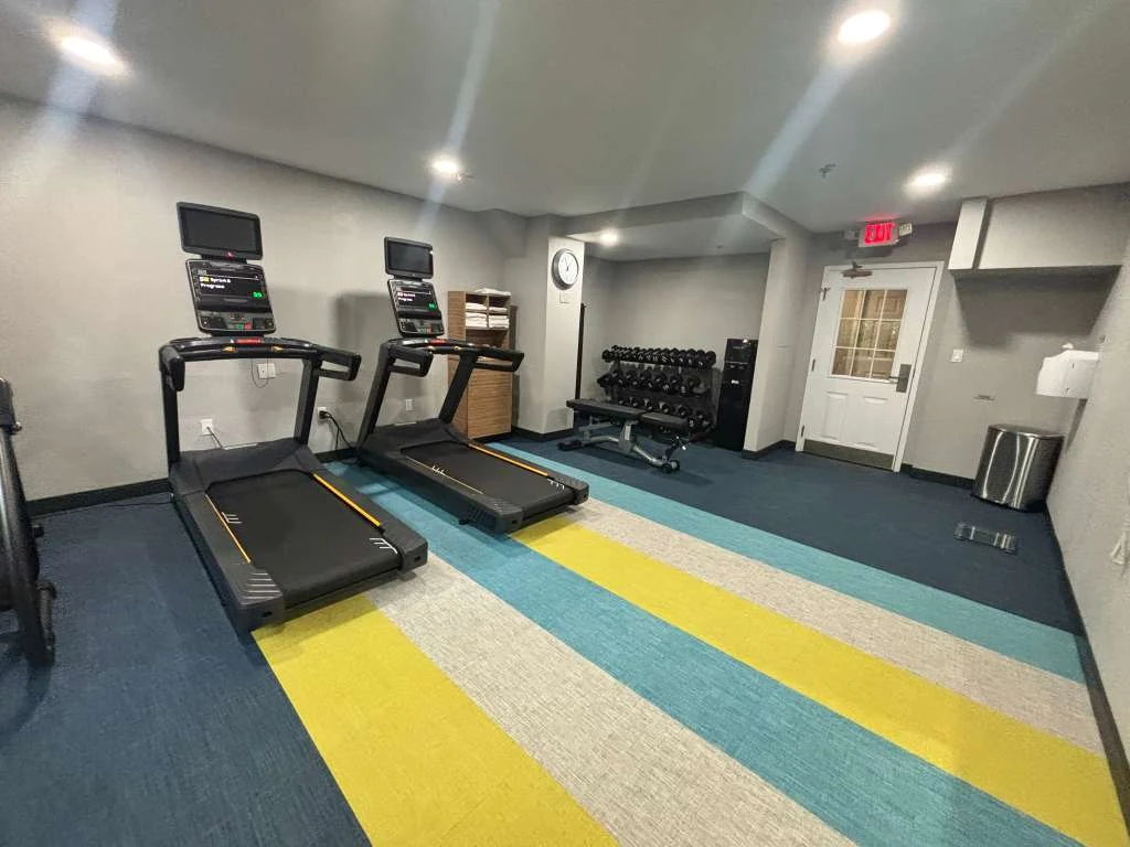 Hotel fitness area with new striped carpet, treadmills, free weights and towel storage at a Weston hotel