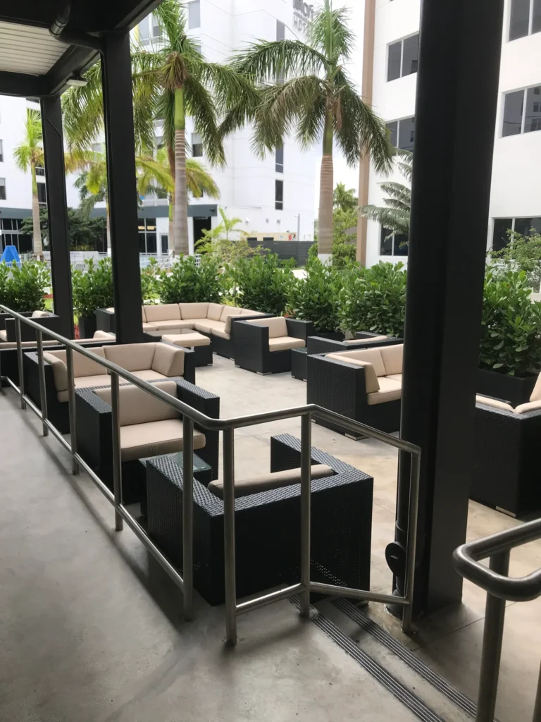 Outdoor hotel lounge with seating area, landscaping and modern furniture constructed in Miami hospitality project