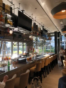 Modern restaurant bar with industrial ceiling, suspended shelving and seating built during commercial construction project in Miami